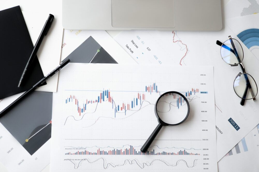 Lente di ingrandimento e occhiali da vista appoggiati su dei grafici stampati