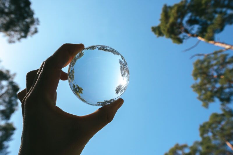 Vista dal basso della mano che tiene la sfera di cristallo contro il cielo
